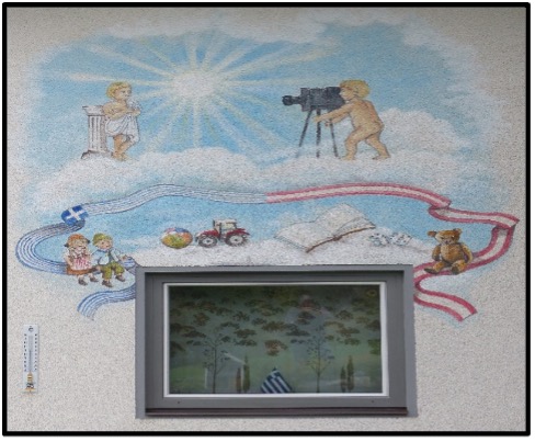 Kunstwand Penk 65 – Wandmalerei von Edith Sulzenbacher: Putten mit Kameras auf Wolken, Spielzeug, österreichische und griechische Flaggenbänder, das große Fenster